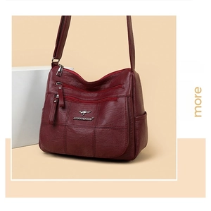 Detail view of burgundy multi-zipper crossbody bag featuring premium lychee texture leather
