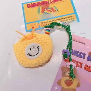 Détail de l'étui à écouteurs jaune crocheté avec smiley et cordon vert tressé à la main