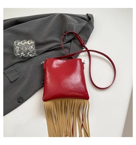 Detail of red studded leather handbag with long khaki fringe and silver hardware accents
