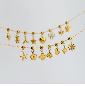 Macro view of gold stainless steel necklace featuring mixed floral and butterfly charms