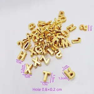 Macro shot of gold letter beads showing dimensions of 1.2x1cm and 0.8x0.2cm hole size