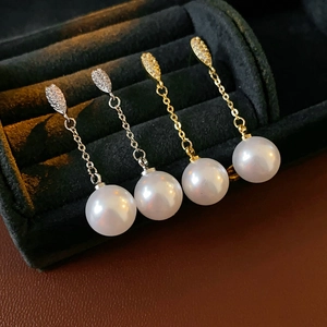Close-up of pearl drop earrings in gold and silver finish on black velvet background