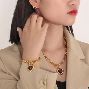 Detailed view of heart-shaped purple glass pendants on a gold necklace and bracelet set