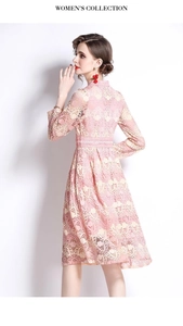 Détails de broderie en dentelle rose sur une élégante robe évasée à manches longues