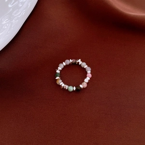 Detailed close-up of beaded elastic ring with pearls and amazonite on dark satin silk