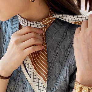 Brown and white striped silk scarf with geometric grid pattern worn as a necktie