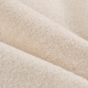 Close-up of soft cream white sherpa fleece fabric showing curly texture and warm material