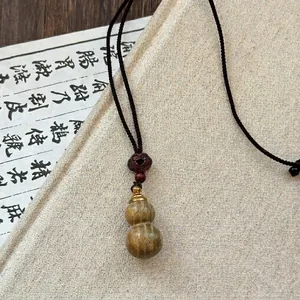 Detailed macro view of a vintage wooden gourd pendant on a brown braided rope necklace