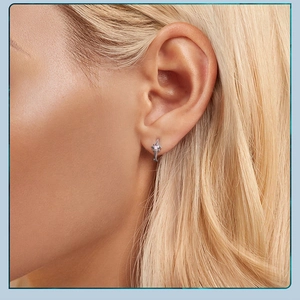 Close-up of star-shaped sterling silver hoop earring with small crystals worn on ear