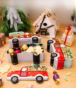 Detailed view of open car-shaped Christmas tin boxes filled with festive candies and cookies