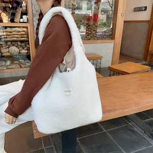 Detailed close-up of fluffy white faux fur tote bag featuring a minimalist brand woven label