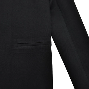 Detail view of the black blazer suit fabric showing the textured chest pocket stitching