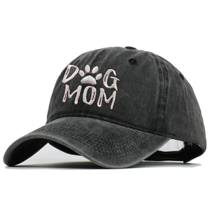 Macro view showing the pink 'DOG MOM' embroidery detail on a washed black cotton baseball cap