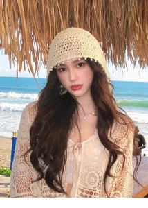 Dettaglio cappello da spiaggia in tessuto beige con perle bianche e motivo traforato