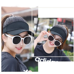 Detailed view of a black sun visor hat worn by a model in an outdoor setting