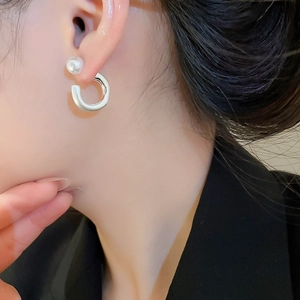 Nahaufnahme eleganter C-förmiger Silberohrringe mit Perlenakzenten an einem Model