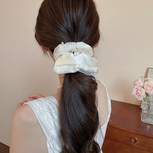 Detail of silk pearl hair scrunchie shown on a ponytail hairstyle with elegant texture