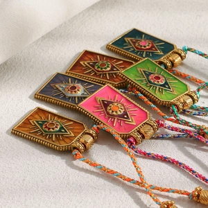 Macro shot of 18K gold plated evil eye pendants with colorful enamel on woven rope