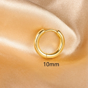 Polished 10mm golden stainless steel huggie hoop earring on champagne satin fabric