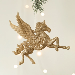 Ornement licorne ailée champagne doré pailleté sur une branche de pin avec effet bokeh