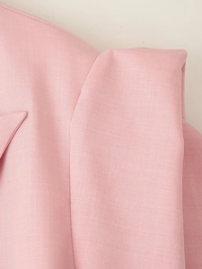 Dettaglio macro del tessuto twill rosa con cuciture su colletto e spalla del blazer