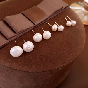 Set of five pairs of round white pearl earrings in various sizes on brown velvet box