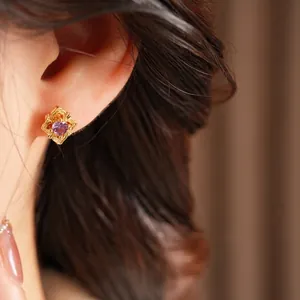 Vintage gold hollow earrings with purple zircon gemstone shown on a model