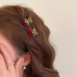 Cute cherry-shaped flocked hair claw clip with pearl accents on brown wavy hair