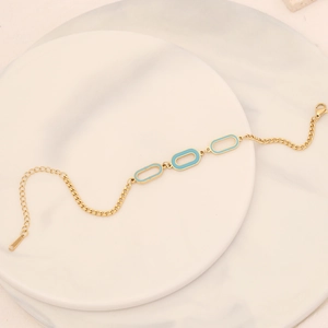 Detailed shot of a gold chain bracelet with blue enamel oval charms on a marble tray