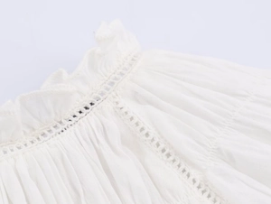 Close-up of white poplin shirt collar featuring intricate eyelet lace and pleated details