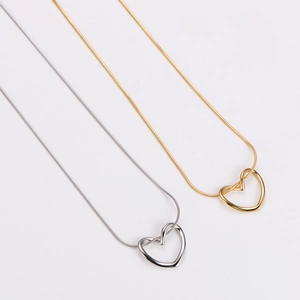 Detail of gold and silver hollow heart pendants on delicate snake chains over white
