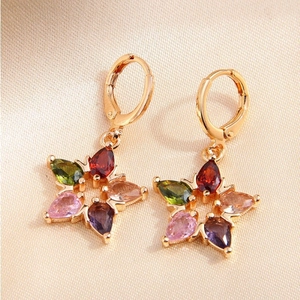 Fashionable gold star earrings featuring colorful zircon stones on a beige silk background