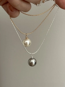 Detail showing elegant gold and silver snake chains with white and grey pearl pendants