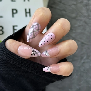 Mandel-Kunstnägel in Rosa mit grauem Karomuster, schwarzen Schleifen und Spitzen-Details