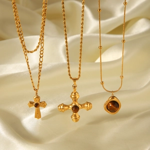 Three-piece set of gold-plated tiger eye cross necklaces on luxury silk background