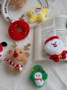 Flat lay of plush Christmas ornaments featuring reindeer, Santa and tree on white fabric