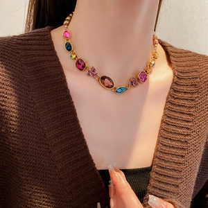 Detail of vintage gold necklace with colorful teardrop gemstones and bow design