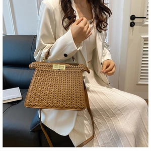 Detailed view of woven brown leather handbag featuring a gold twist lock and top handle