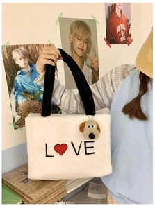 Detail of white plush tote bag featuring red heart embroidery and cute dog charm pendant