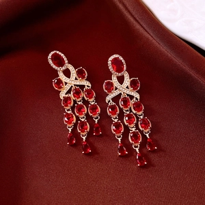 Detail view of gold earrings with red rubies and cubic zirconia on red silk fabric