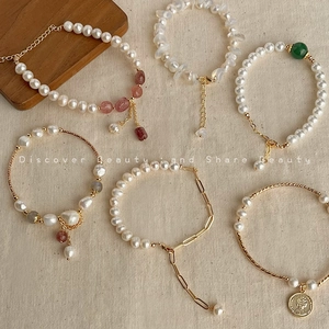 Flat lay of baroque pearl bracelets with natural gemstones and gold coin pendant detail