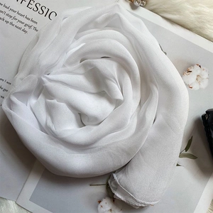 Detail of pure white silk scarf folded into a rose shape on a soft textured background