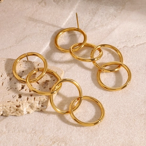 Minimalist gold tiered geometric circle hoop earrings on natural stone background