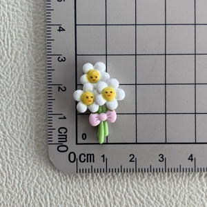Vue macro d'une fleur marguerite en résine avec nœud rose sur tapis de mesure de 3 cm
