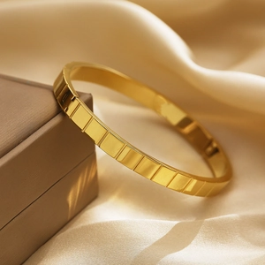 Dettaglio ravvicinato del bracciale dorato con motivo a scacchi su una scatola regalo