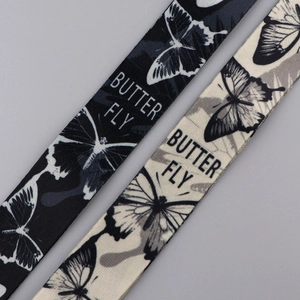 Detail of butterfly pattern fabric lanyards in black and beige with butterfly printing