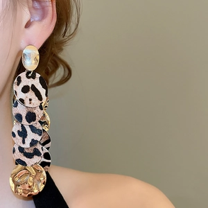 Gros plan de boucles d'oreilles pendantes à imprimé léopard et disques dorés sur un mannequin