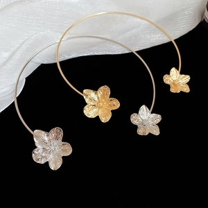 Detail of metallic flower choker with intricate petal textures in gold and silver finish