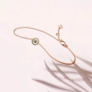 Close-up of rose gold Evil Eye bracelet with blue crystal center and leaf shadow