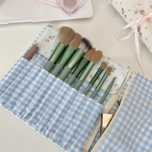Floral makeup brush set with green metal handles and blue gingham storage pouch